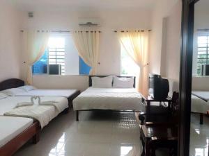 a bedroom with two beds and a tv and windows at Ngoc Phung Guesthouse in Vung Tau