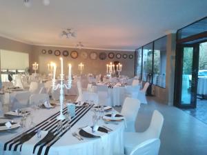 a banquet hall with white tables and white chairs at Willow Banks Lodge in Parys