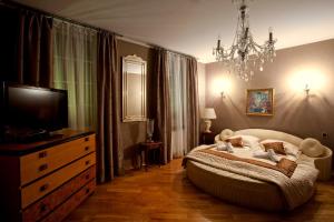 a bedroom with a bed and a television and a chandelier at Aparthotel Oberża in Krakow