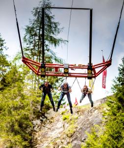 Trzech ludzi na huśtawce liny w lesie w obiekcie Fit und Fun Sportherberge w mieście Kötschach