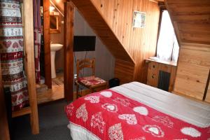 a bedroom with a red bed and a bathroom at Hotel Le Terminus in Le Bourg-dʼOisans