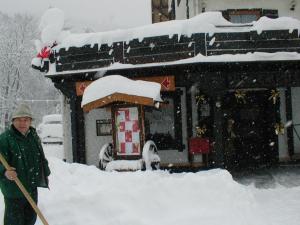 a man standing in the snow with a shovel at Garni Hotel Adler Post in Baiersbronn