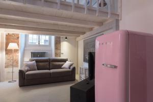 a pink refrigerator in a living room with a couch at New loft in the heart of Bologna in Bologna