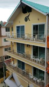 un edificio de apartamentos con balcones, mesas y sillas en Panjai's Place, en Cha Am