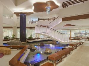 a large lobby with a pond and stairs in a building at Sheraton Okinawa Sunmarina Resort in Onna