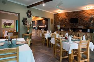 un restaurante con mesas y sillas y una pared de ladrillo en Colesview Guest House, en Colesberg