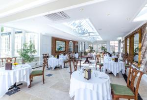 a restaurant with white tables and chairs and windows at Goldsborough Hall in Knaresborough
