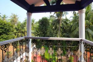 a balcony with an iron railing and palm trees at The Pereira's Goan Homestay Villa in Vasco Da Gama