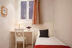 a small bedroom with a bed and a desk and a window at Bcngotic in Barcelona
