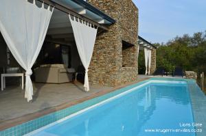 a swimming pool in front of a house at Kruger River Villas - LionsGate in Marloth Park