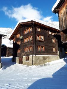 un gran edificio de madera con nieve en el suelo en Alpensonne en Reckingen - Gluringen