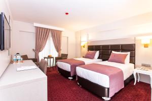 a hotel room with two beds and a desk at Perla Arya Hotel in Izmir