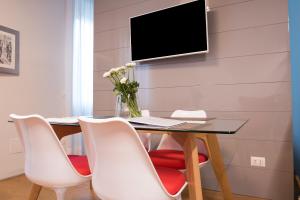 a dining room table with white chairs and a tv on a wall at Milano Repubblica Suite Centro in Milan