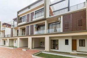 un edificio de apartamentos con balcones y un patio en StayVista's Greenwoods Villa 7 - City-Center Villa with Private Pool, Terrace, Lift & Ping-Pong Table, en Lonavala