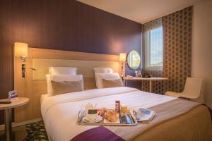a hotel room with a bed with a tray of food on it at Mercure Mulhouse Centre in Mulhouse
