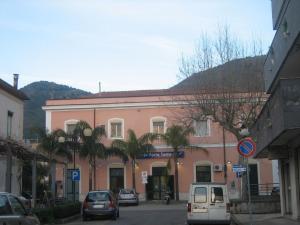 a pink building with cars parked on a street at Rex Bed & Business in Praia a Mare