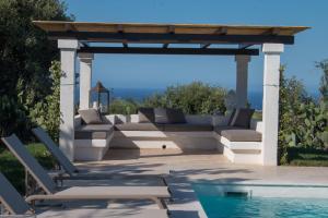 a pergola over a swimming pool with chairs and a couch at Villa del Vento in Polignano a Mare