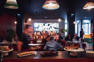 a group of people sitting in a restaurant with food at BOMA easy living hotel By Stay Collection in Strasbourg