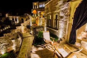 a balcony with chairs and a building at night at Azure Cave Suites - Cappadocia in Göreme +75 photos