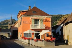 an orange building with a balcony on a street at Auberge Buissonniere in Gresse-en-Vercors