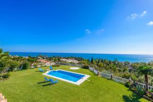 ベナルマデナにあるCubo's Villa Las Colinasのスイミングプールと海を望む庭園の空中ビュー
