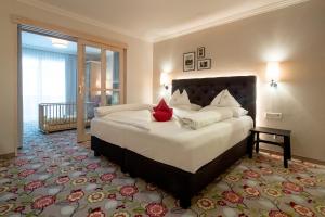 a bedroom with a large bed with a red pillow at Familienhotel Felsenhof in Flachau