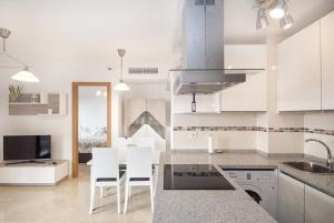 フエンヒロラにあるCubo's Apartamento Espana Fuengirola 2Bの白いキャビネット、テーブルと椅子付きのキッチンが備わります。