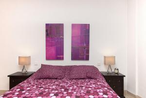 フエンヒロラにあるCubo's Apartamento España 2C Fuengirolaのベッドルーム1室(紫色のベッド1台、壁に絵画2点付)