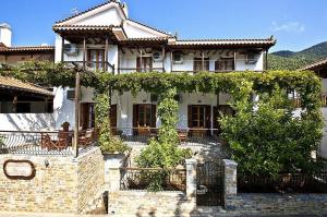 a large white house with ivy growing on it at Athina Apartments in Neo Klima