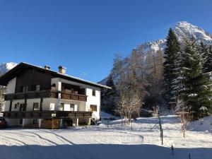 una casa nella neve con montagne sullo sfondo di Haus Sonnenspitze - Fam. Nessler a Biberwier