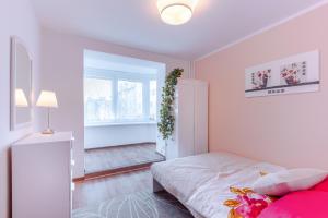 een witte slaapkamer met een bed en een raam bij Apartament na starowce in Kołobrzeg