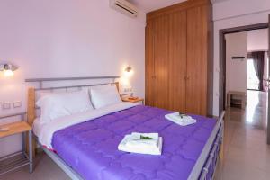 duże fioletowe łóżko w sypialni ze stołem w obiekcie Paleochora Apartments w mieście Palaiochóra