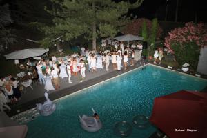 a group of people standing around a swimming pool at Le Safari Hotel Restaurant in Carpentras
