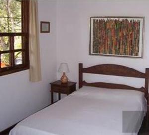 a bedroom with a bed and a window at Pousada do Capão in São Gonçalo do Rio das Pedras