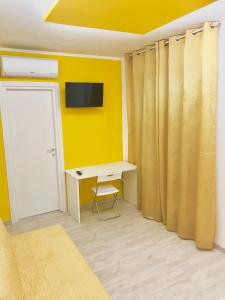 Habitación con escritorio y pared amarilla. en B&B Fratelli Tommasini Salerno, en Salerno