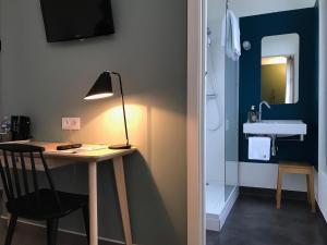 a room with a desk with a lamp and a sink at Hotel de France in Saint-Pol-de-Léon