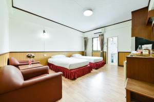 a room with two beds and a chair and a couch at Nice Palace Hotel in Bangkok +35 photos