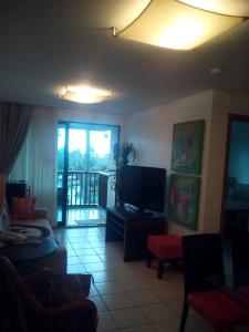 sala de estar con sofá y TV en Flat Resort Marulhos, en Porto de Galinhas