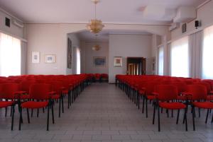an empty room with red chairs in a building at Garden Rooms in San Giovanni la Punta