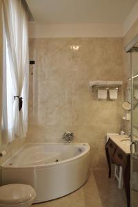 a white bath tub in a bathroom with a sink at Pesaro Palace in Venice