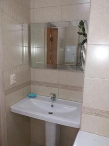 lavabo blanco en el baño con espejo en Квартира en Almaty