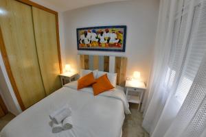 マラガにあるApartamentos Velaのベッドルーム1室(白いベッド1台、オレンジ色の枕付)