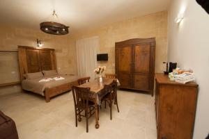 
a room with a bed, table, chairs, and a dresser at Sassi e Virtù in Matera
