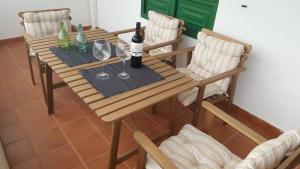 drewniany stół z 2 butelkami i 2 kieliszkami wina w obiekcie Apartamentos Casa Cipri w mieście Playa Blanca