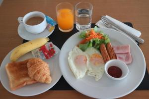 una mesa con dos platos de desayuno y una taza de café en L42 Hostel Suvarnabhumi Airport en Lat Krabang