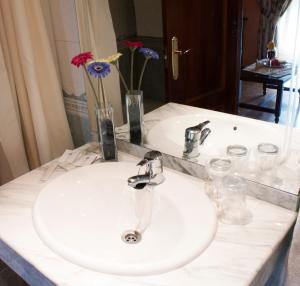 La salle de bains est pourvue d'un lavabo blanc et d'un miroir. dans l'établissement Albenzaire Hotel Asador, à Fuensanta