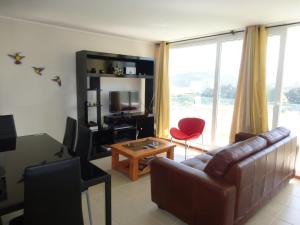 a living room with a couch and a table and a television at Papudo Laguna in Papudo