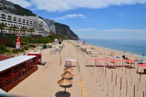 a beach with chairs and umbrellas and the ocean at Felp Sesimbra Beach 1006 in Sesimbra