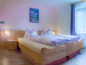 una camera da letto con un grande letto in legno con cuscini blu di Hotel Alpenfriede a Curon Venosta