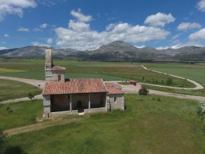 an old building in a field with mountains in the background at Casa Rural Majada Palentina in Villanueva de Arriba